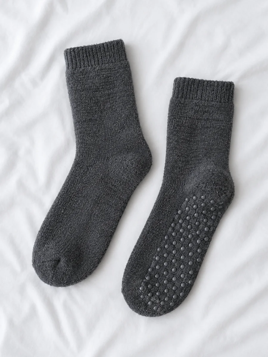 Calcetines de casa con suela antideslizante, gris marengo, extendido sobre sábana blanca